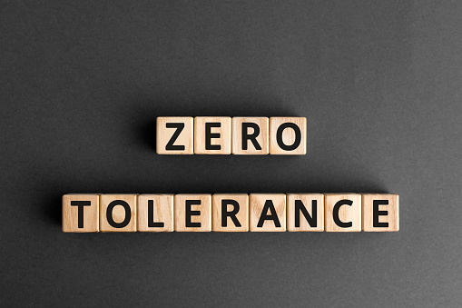 CAPTZero tolerance - words from wooden blocks with letters, severely punishing all unacceptable behaviour, zero tolerance concept, gray background